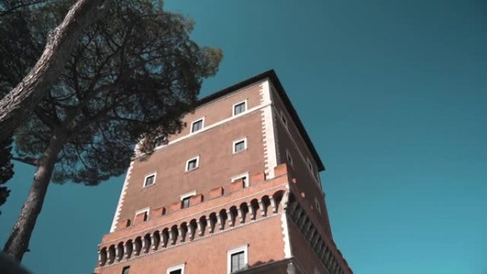 威尼斯宫著名塔在阳光下的低角度，惊人的蓝色狡猾的背景和生长的松树，罗马市中心特色罗马建筑立面的塔，意