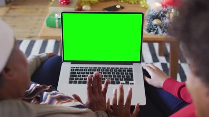 非裔美国母亲与女儿进行笔记本电脑圣诞节视频通话，并带有绿屏