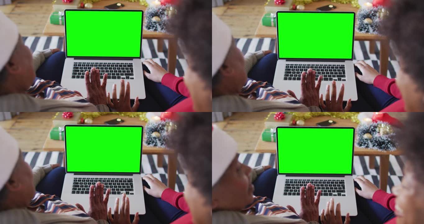 非裔美国母亲与女儿进行笔记本电脑圣诞节视频通话，并带有绿屏