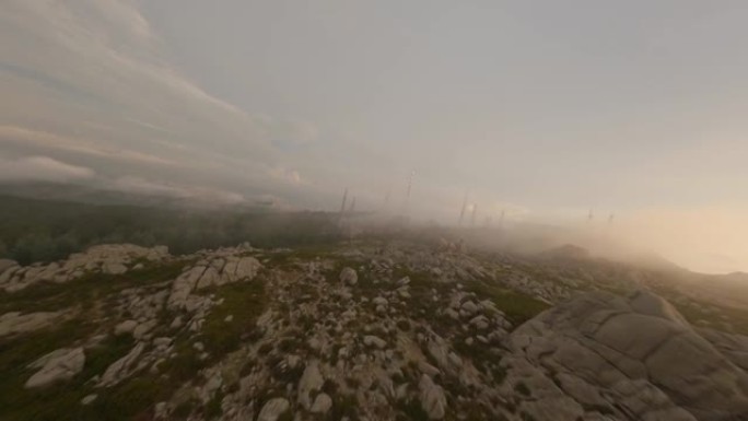 FPV视频，山地冲浪，在美丽的日出期间，在带有花岗岩山脉和天线农场的云层中高速飞行。意大利撒丁岛的林