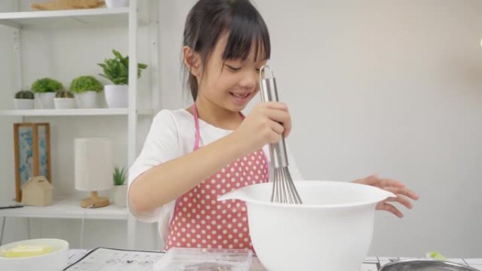 快乐的亚洲孩子在家里学习做饼干，女孩在搅拌碗里搅拌面粉。