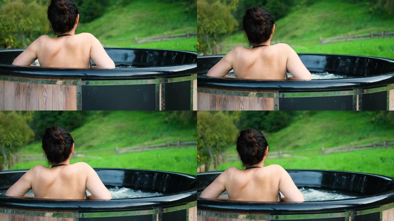 年轻女子在露天浴池里，可以看到山景。