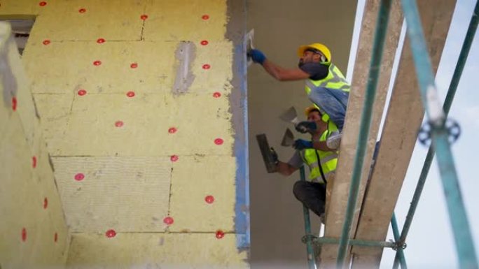 建筑工人在建筑立面上涂石膏