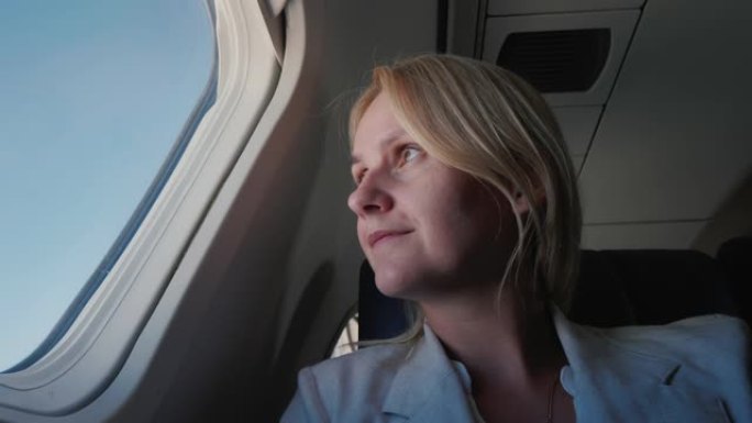 一位自信的女乘客的肖像，在飞机上飞行，看着窗外