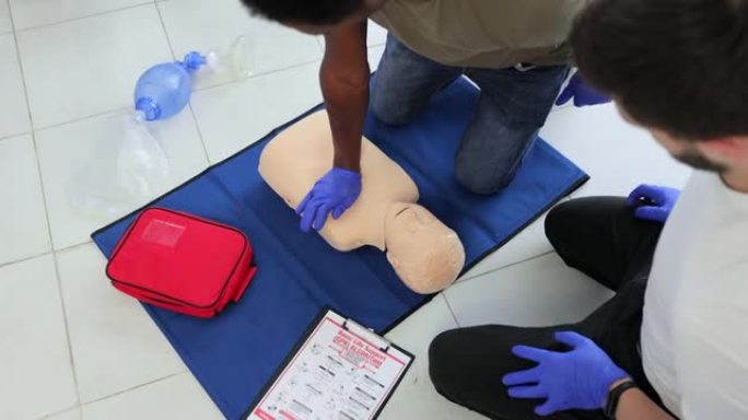 青少年假人练习心肺复苏术胸部按压的学生特写。