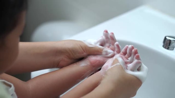 母亲洗女儿的手，以防止病毒，洗脸池中的细菌和细菌。