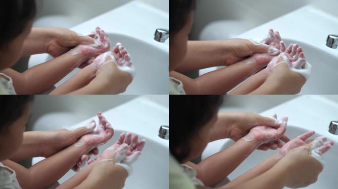 母亲洗女儿的手，以防止病毒，洗脸池中的细菌和细菌。