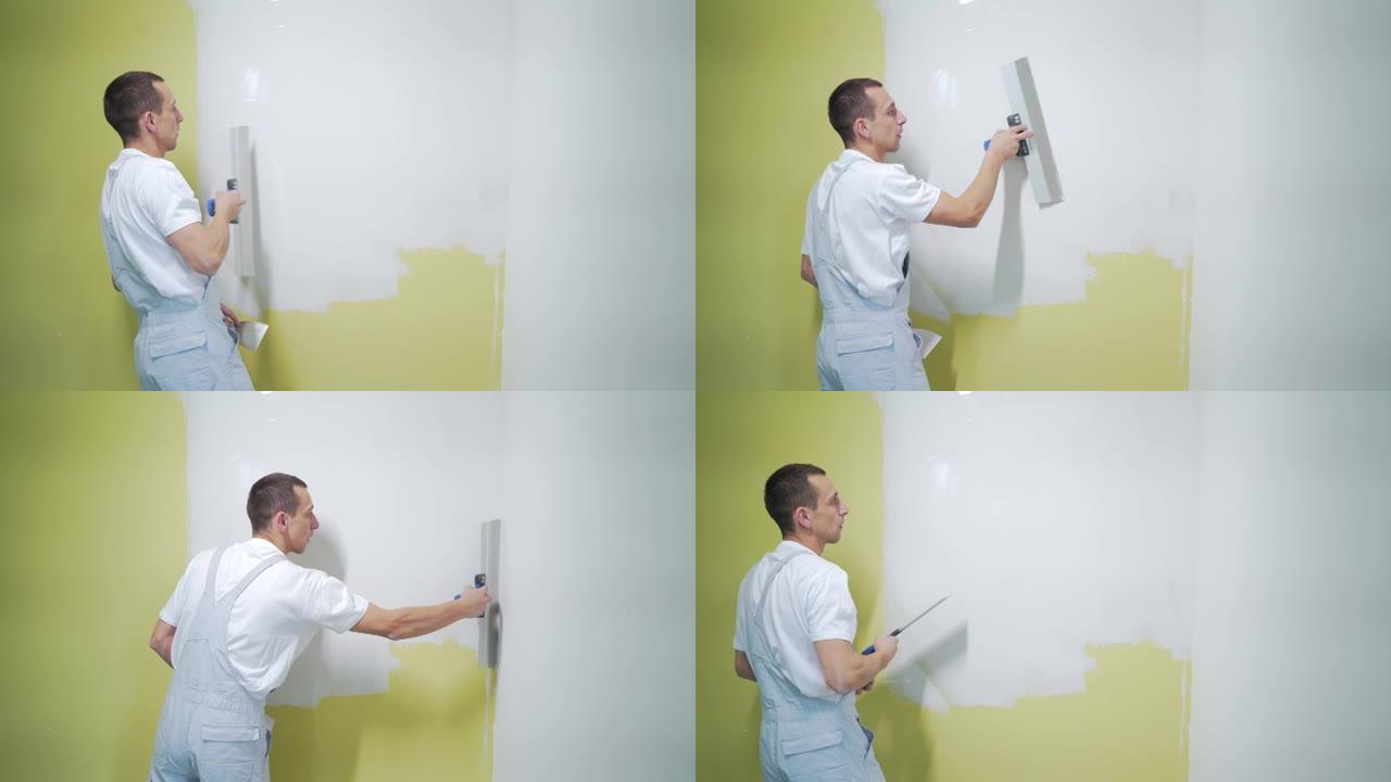 经验丰富的修理工正在抹灰墙壁，使用刮刀，油灰刀和白色现代砂浆，粉刷
