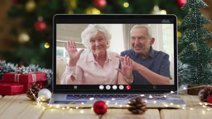 一对白人老夫妇在圣诞树旁用笔记本电脑视频通话