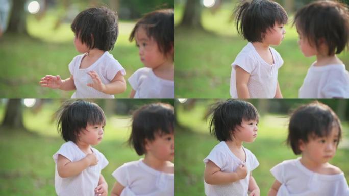 可爱的亚洲中国双胞胎男婴看着人们在草坪公园好奇地慢跑经过