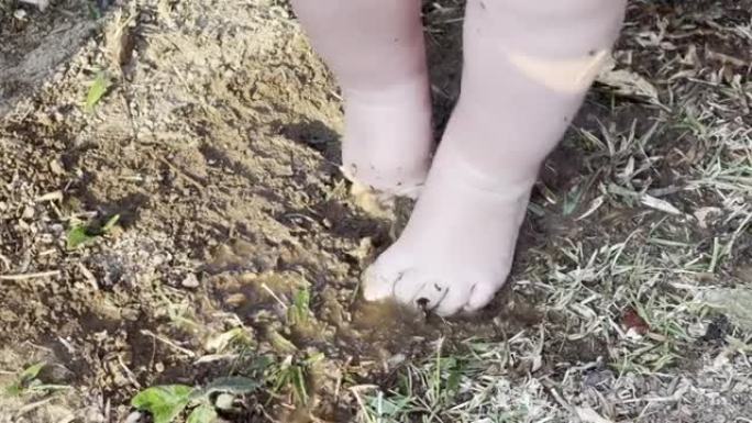可爱的乱七八糟的婴儿脚踩着泥水