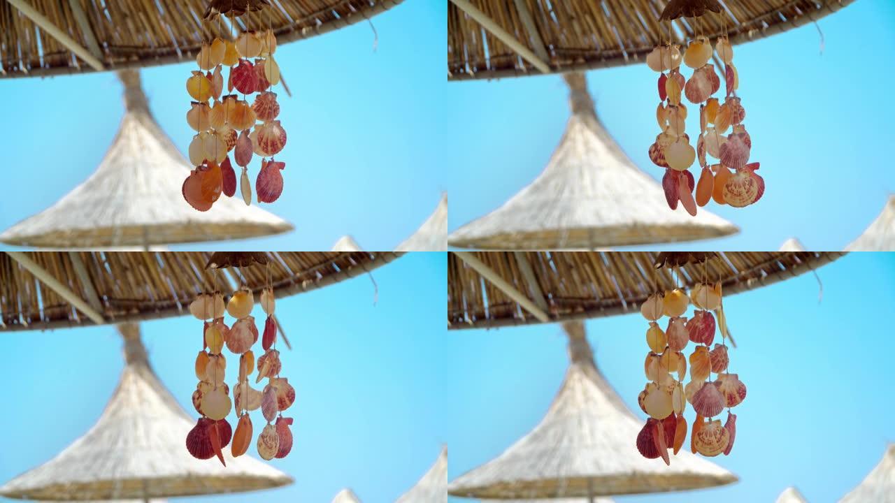 在热带海滩上的夏季brezee上挥舞着蓝色天空 (风铃) 的弦贝壳装饰的特写镜头