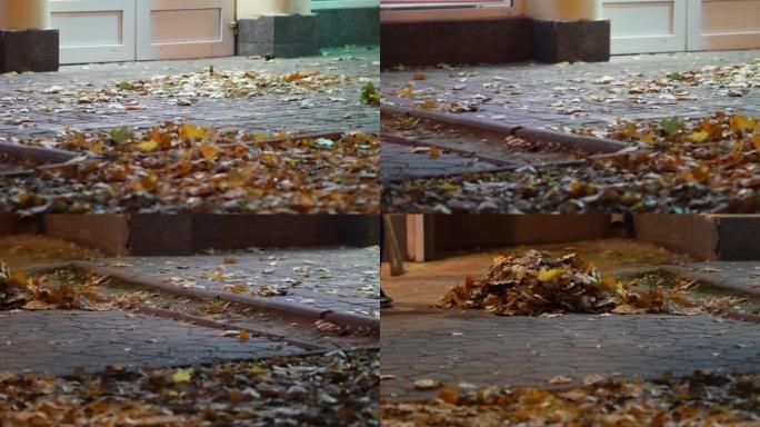 人行道上的秋叶。看门人扫堆里的树叶