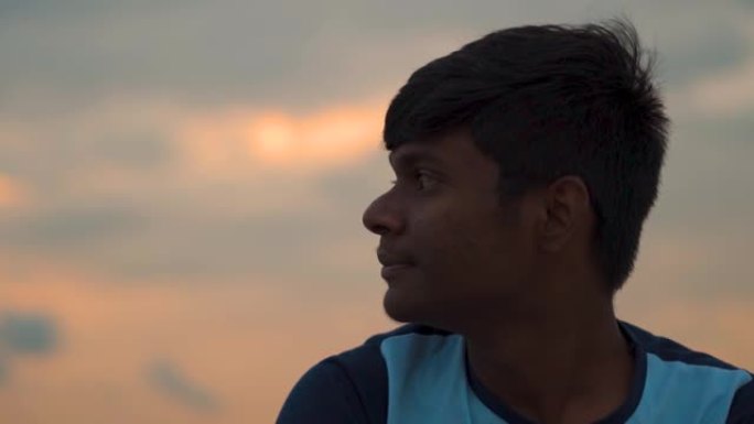 一个印度孩子在日落时侧视的肖像。孩子迷失在沉思中侧视。上学的孩子把目光从镜头上移开，想着他的未来。