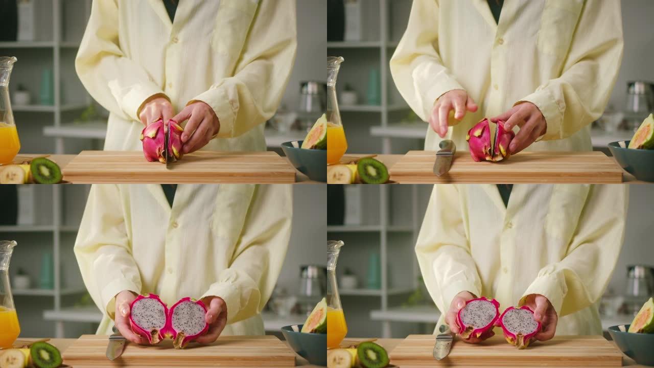 女人切pitahaya特写镜头，将火龙果切成两半，准备烹饪冰沙的原料，不含糖的健康甜鸡尾酒。餐桌上的