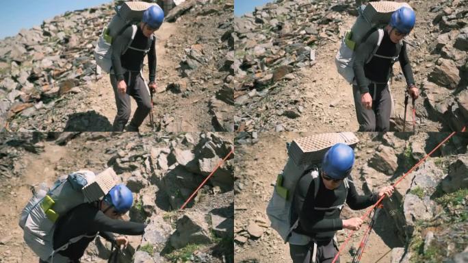 在山上下降时，一名登山者拿着一个大背包走近绳子，抓住了它。