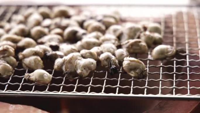 在粘土火锅上烤牡蛎特写，在烤架上用燃烧的木炭煮牡蛎