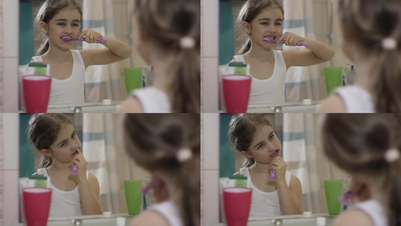 特写肖像年轻的小女孩在浴室刷牙看着镜子反射。日常口腔卫生。快乐肖像可爱的高加索无牙儿童在浴室刷牙。