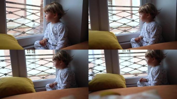 坐在窗边向外看的孩子。蹒跚学步的婴儿坐在窗边