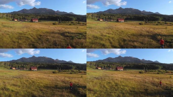 年轻兄弟的无人机在山顶阴影下的一个历史悠久的牧场前的草地上奔跑。科罗拉多州西南部的Telluride