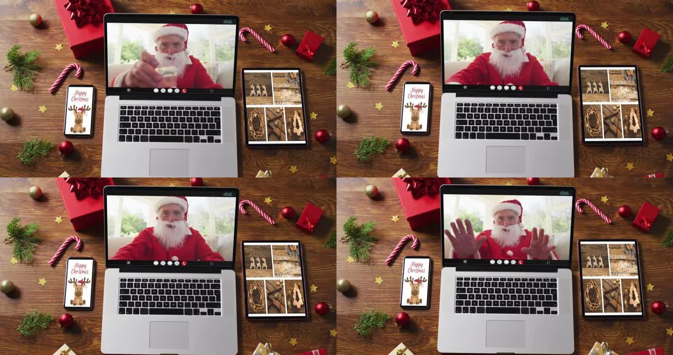 快乐的高级高加索圣诞老人在笔记本电脑上进行视频通话，配有智能手机、平板电脑圣诞装饰品