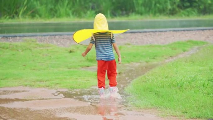 亚洲小男孩在雨中玩水。