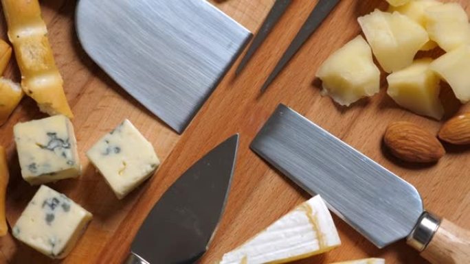 切片奶酪，坚果，葡萄，蜂蜜和小刀放在木盘上。旋转