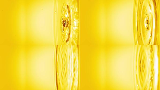 黄色水滴落在透明液体的表面上，形成圆圈