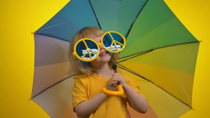 黄色背景工作室里戴着彩虹伞的大滑稽眼镜的女孩