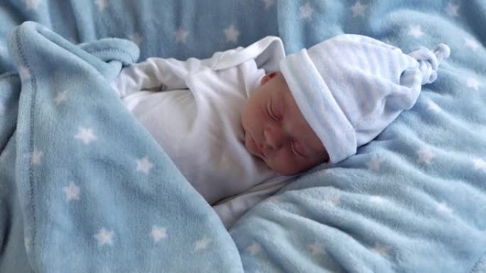 初生婴儿脸部肖像的中期计划早期在蓝星背景上微星睡觉。孩子在帽子上生命的开始。婴儿，分娩，出生的最初时