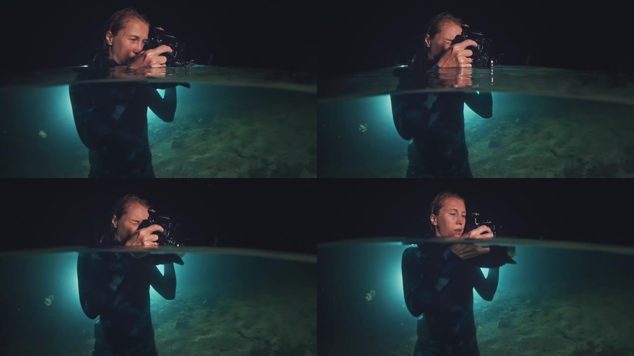 夜湖水下摄影师。穿着潜水服的年轻女子将相机放在水下房屋中，晚上在湖中拍照。