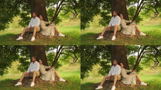 年轻夫妇喜欢在公园的树下背靠背坐着