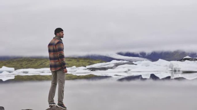 游客站着欣赏冰岛的湖泊和冰川融化