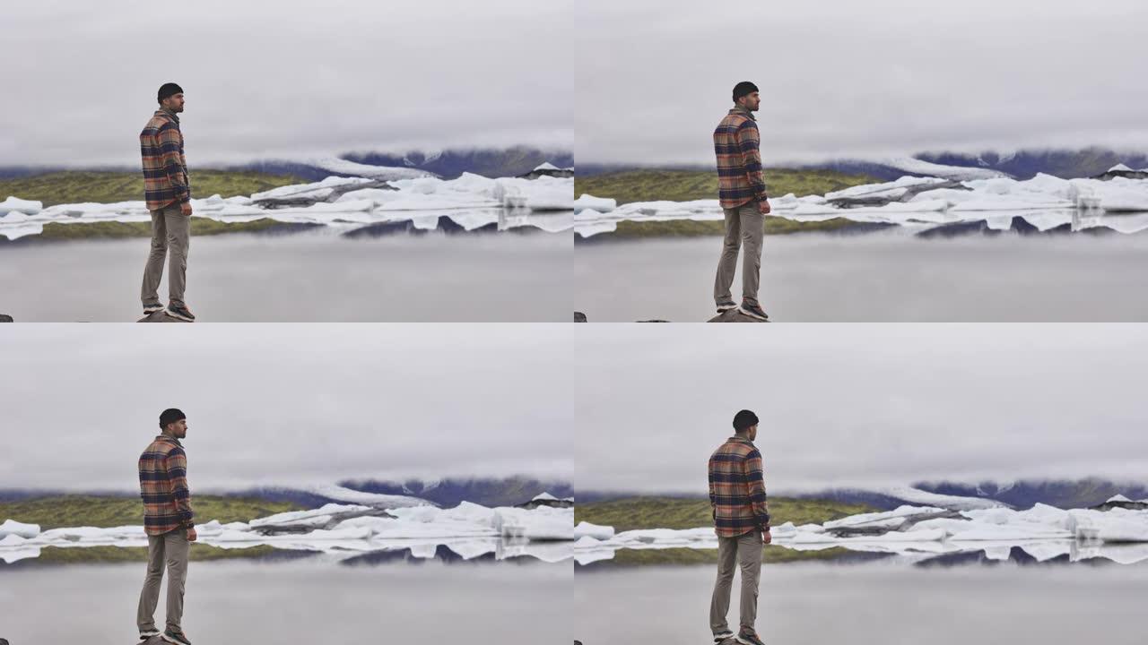 游客站着欣赏冰岛的湖泊和冰川融化
