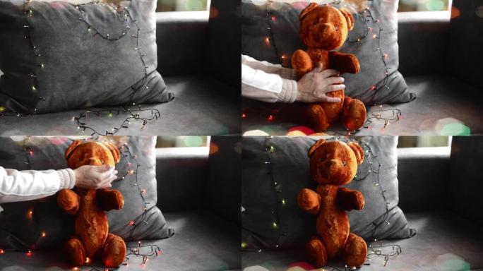 女人的手把一只老熊放在沙发上的花环里。为假期做准备。