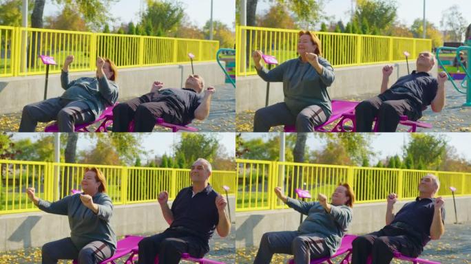 活跃的老年夫妇在户外模拟器上做运动。退休期间，在公园或花园中进行户外运动，以健康和健身。