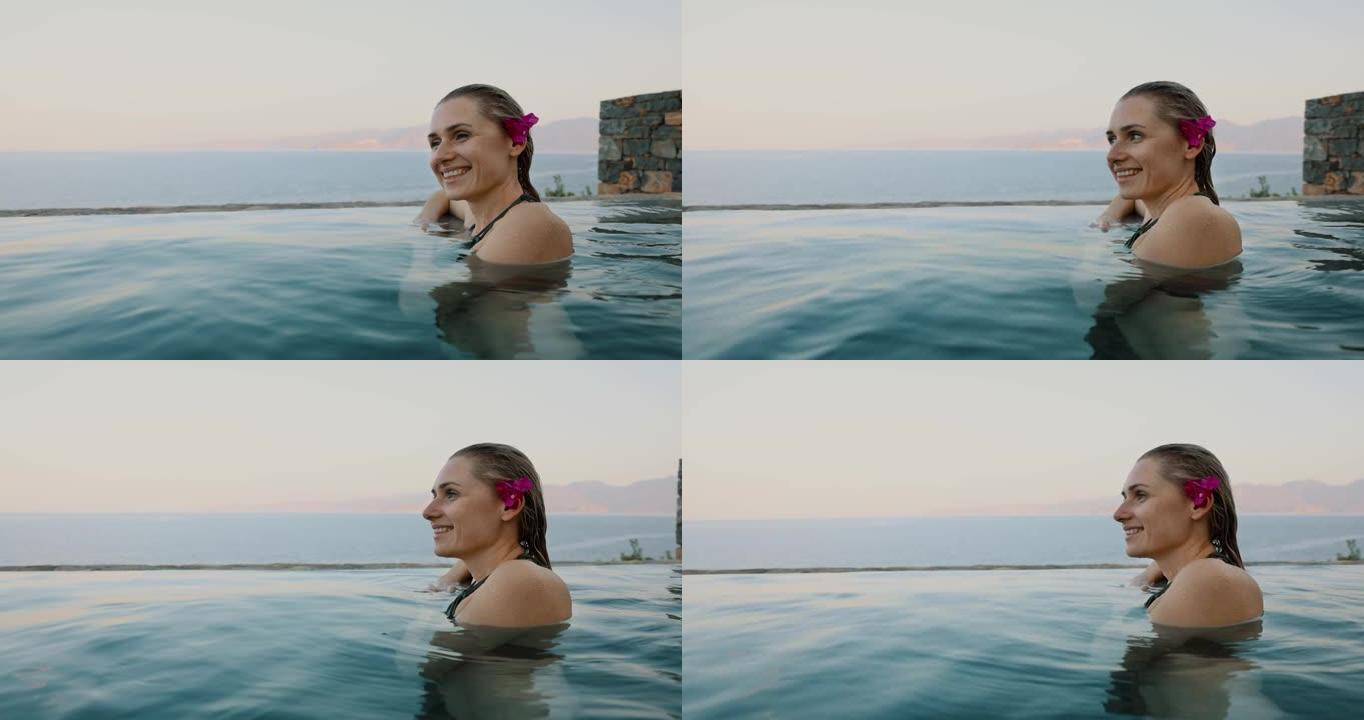 微笑的年轻女子在无边的海景游泳池放松