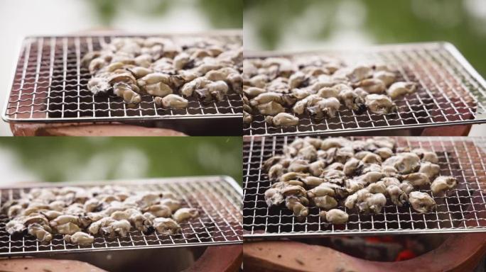在粘土火锅上烤牡蛎特写，在烤架上用燃烧的木炭煮牡蛎