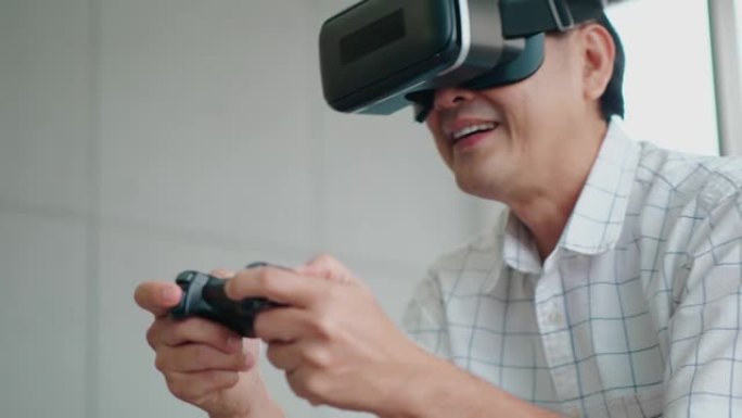 资深亚洲男子手持摇杆戴虚拟现实眼镜VR在客厅玩游戏科技生活方式人度假