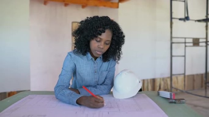 快乐的非洲裔美国女经理在木结构房屋建造期间修改蓝图的肖像