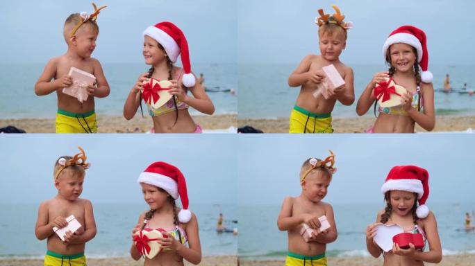 沙滩上戴着圣诞老人帽子和鹿角的孩子。小男孩和女孩在跳舞，微笑着看着镜头。圣诞快乐。寒假。大海在背景中