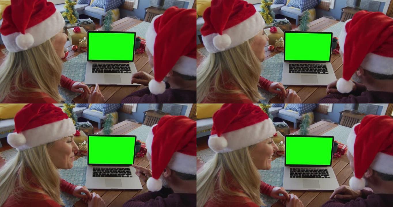 戴着圣诞老人帽子的白人夫妇在绿色屏幕上进行笔记本电脑圣诞节视频通话