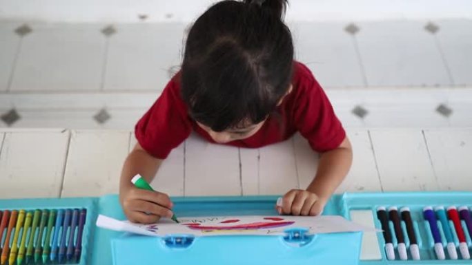 用彩色颜料在纸上特写肖像儿童画。可爱的小女孩坐着画画。