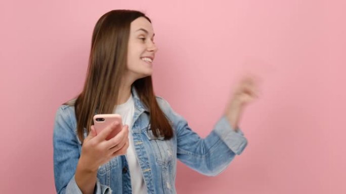 年轻的千禧一代女性手持使用手机指指手放在工作区复制空间模型促销区域，穿着牛仔夹克，在工作室里孤立地摆