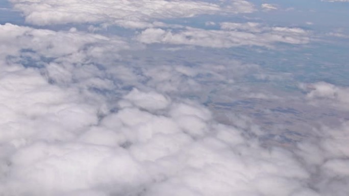 飞机在云层上方飞过美丽的土地，上面是蓝天