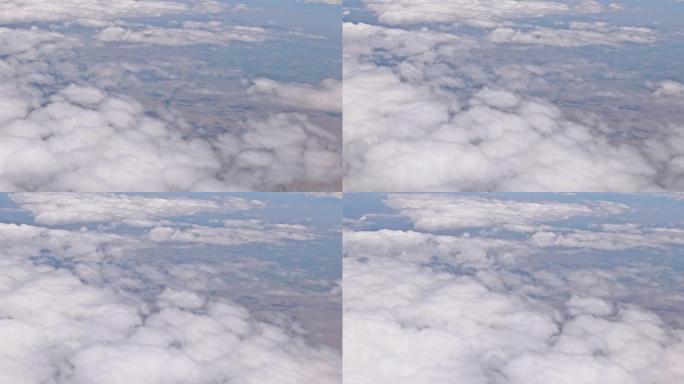 飞机在云层上方飞过美丽的土地，上面是蓝天