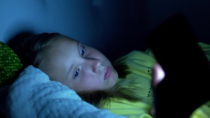 一名女学生上床睡觉，在智能手机上阅读信息。