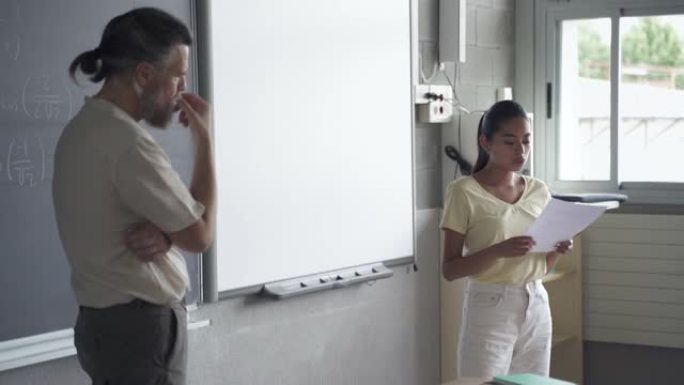 拉丁少年学生读作文给同学和老师。教室里的西班牙裔女孩