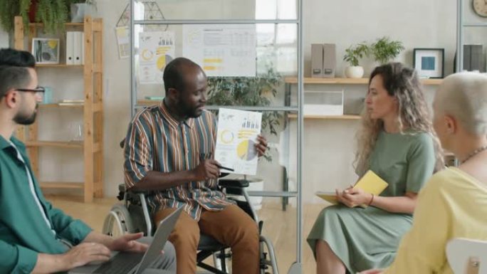 坐在轮椅上的非洲人在办公室会议上介绍商业计划