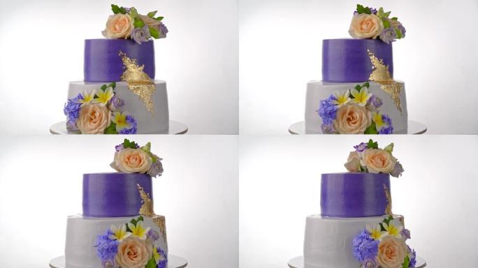 令人愉快的节日奶油双层蛋糕配紫色玫瑰。在背景中旋转。为了婚礼。